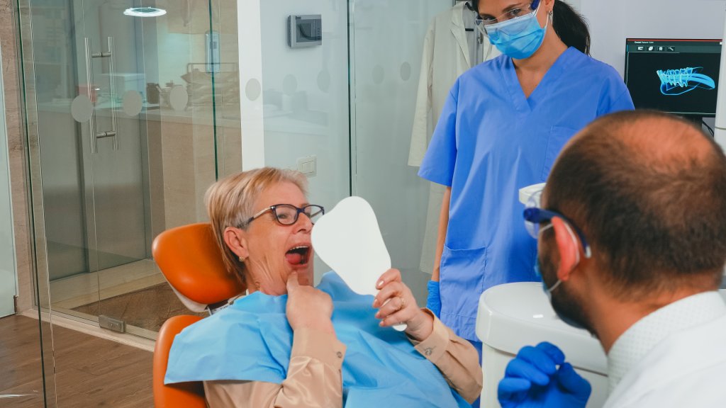 השתלת שיניים בגאורגיה - אישה מסתכלת במראה לאחר ניתוח